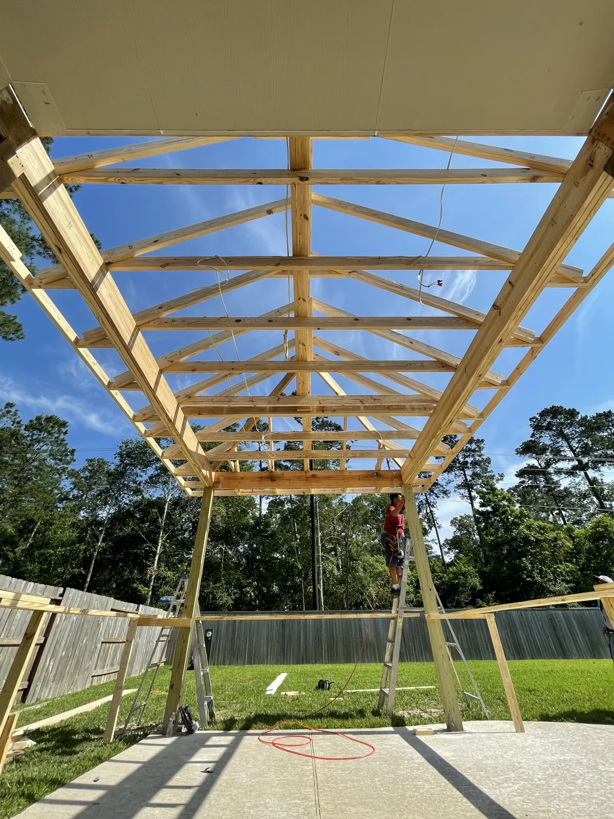 Close-up view of exposed wood roof trusses and rafters for a covered patio under construction