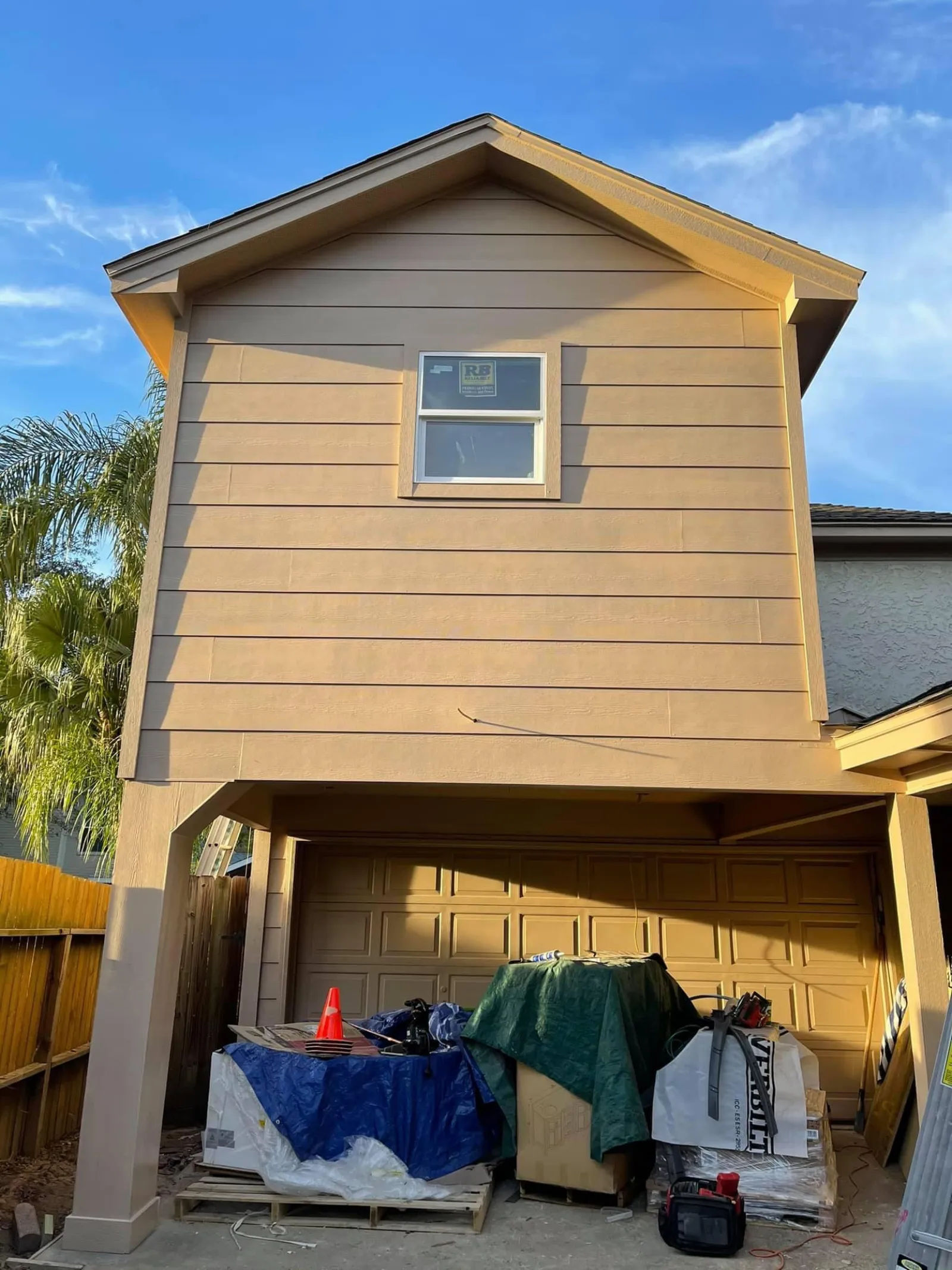 Completed second-story room addition with siding and a window, viewed from the driveway