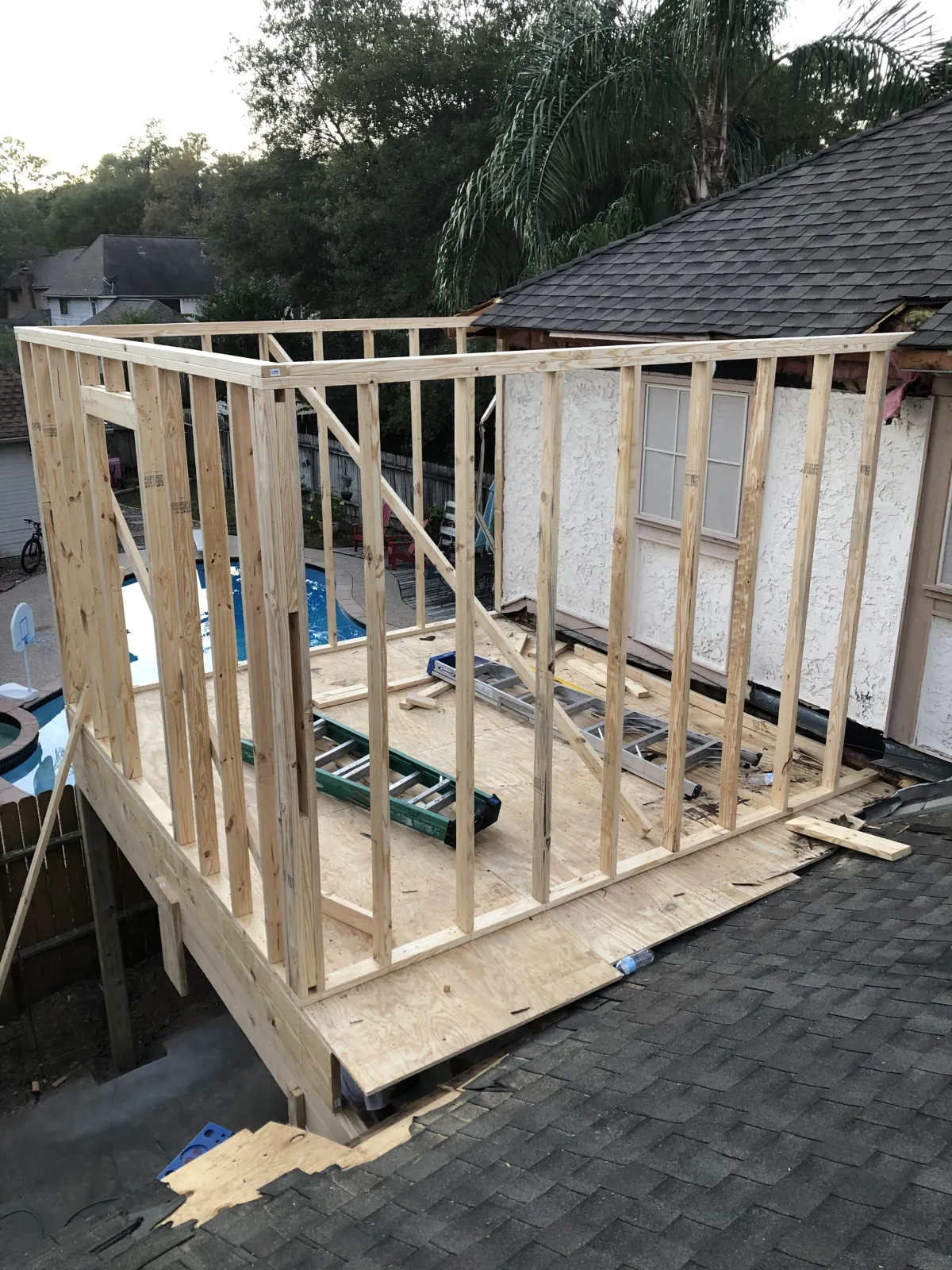 Aerial view of exposed roof rafters and sheathing on a second-story room addition under construction