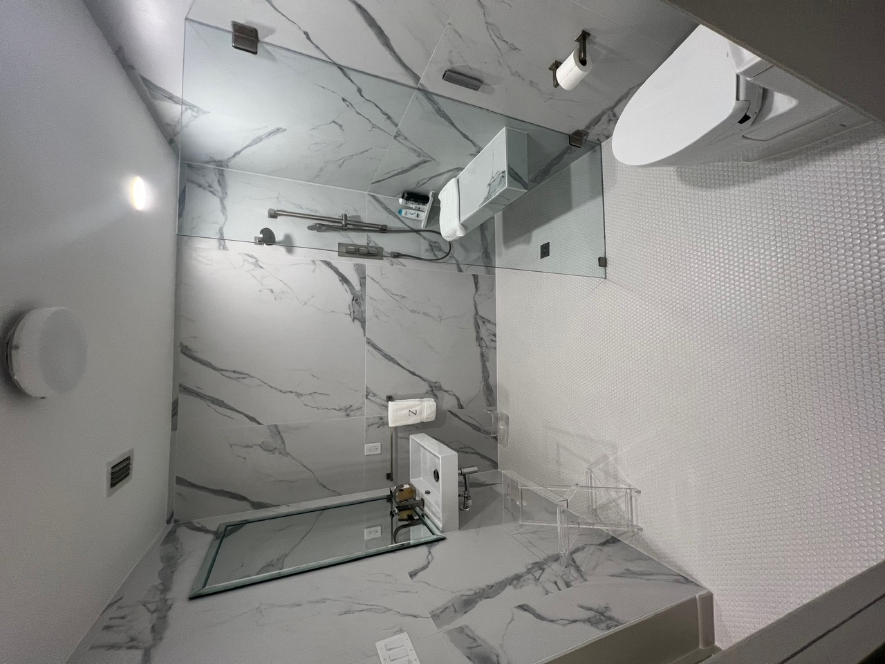 Modern bathroom with marble-look porcelain walls and frameless glass shower