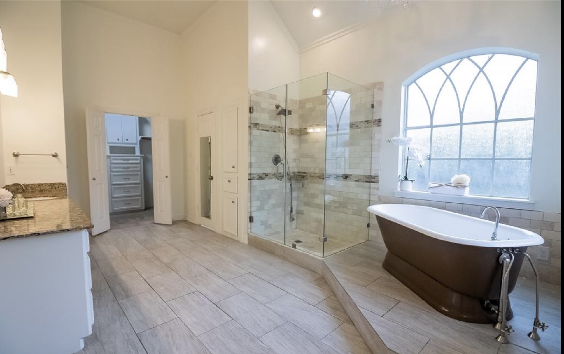Master bathroom with bronze freestanding tub and arched Gothic window
